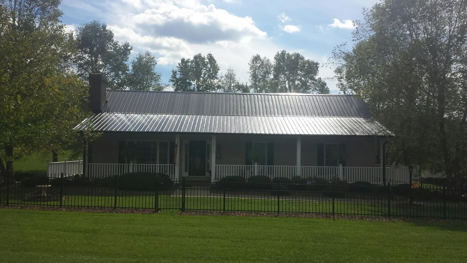 Gray metal roof on a brick ranch with a full width front porch — Gutter Guard Installation work by our crew in Weatherford